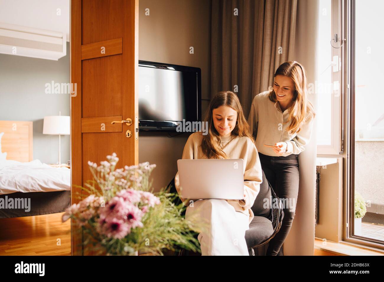 Amici felici che acquistano online con carta di credito tramite laptop in camera d'albergo durante le vacanze Foto Stock