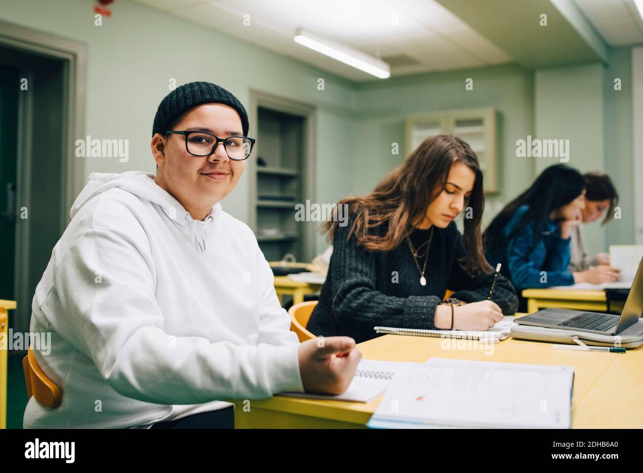 Ritratto di sorridente studente di scuola superiore seduto da un compagno di classe in classe Foto Stock