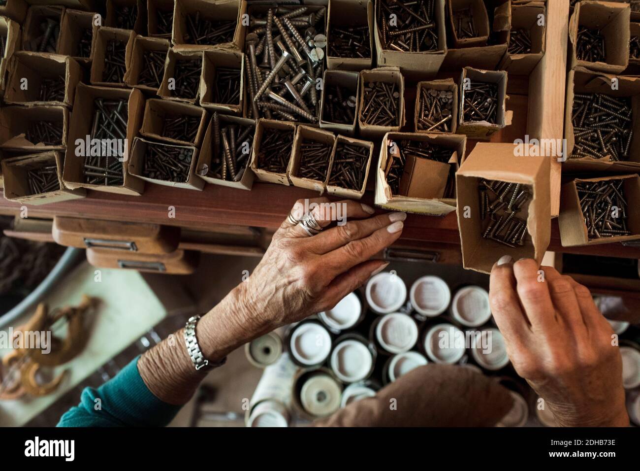 Mani di senior donna addetto alle vendite rimuovere chiodi da cartone box in negozio di hardware Foto Stock