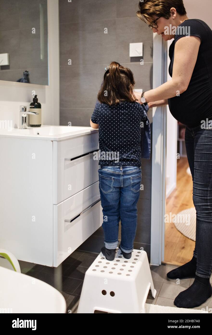 Madre che assiste la figlia nel lavaggio delle mani a casa Foto Stock