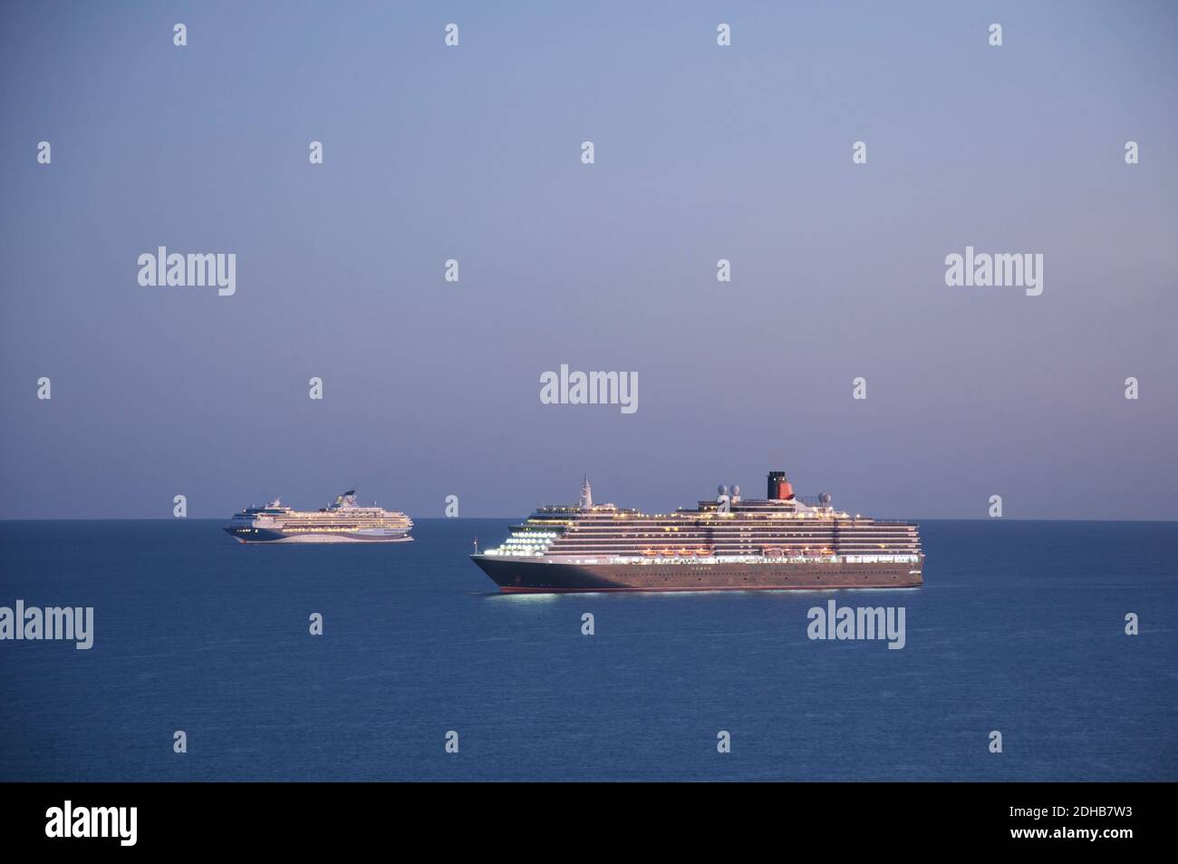 Cunard transatlantico Queen Victoria e nave da crociera Marella Explorer ancorati a Weymouth Bay al tramonto. Mogled durante la pandemia di Covid-19. Dorset. Foto Stock