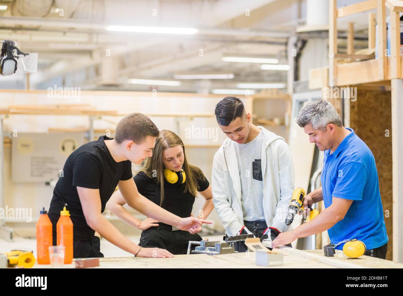 Istruttore maschile che spiega la seminatrice elettrica sulla tavola ai partecipanti a. banco da lavoro Foto Stock