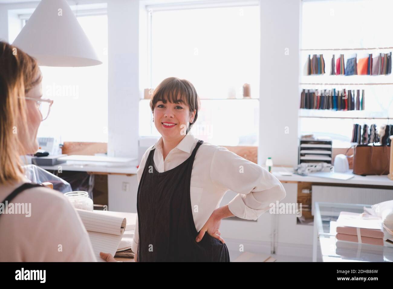 Ritratto di sorridente imprenditore femminile in piedi con la mano sull'anca in officina di tappezzeria Foto Stock