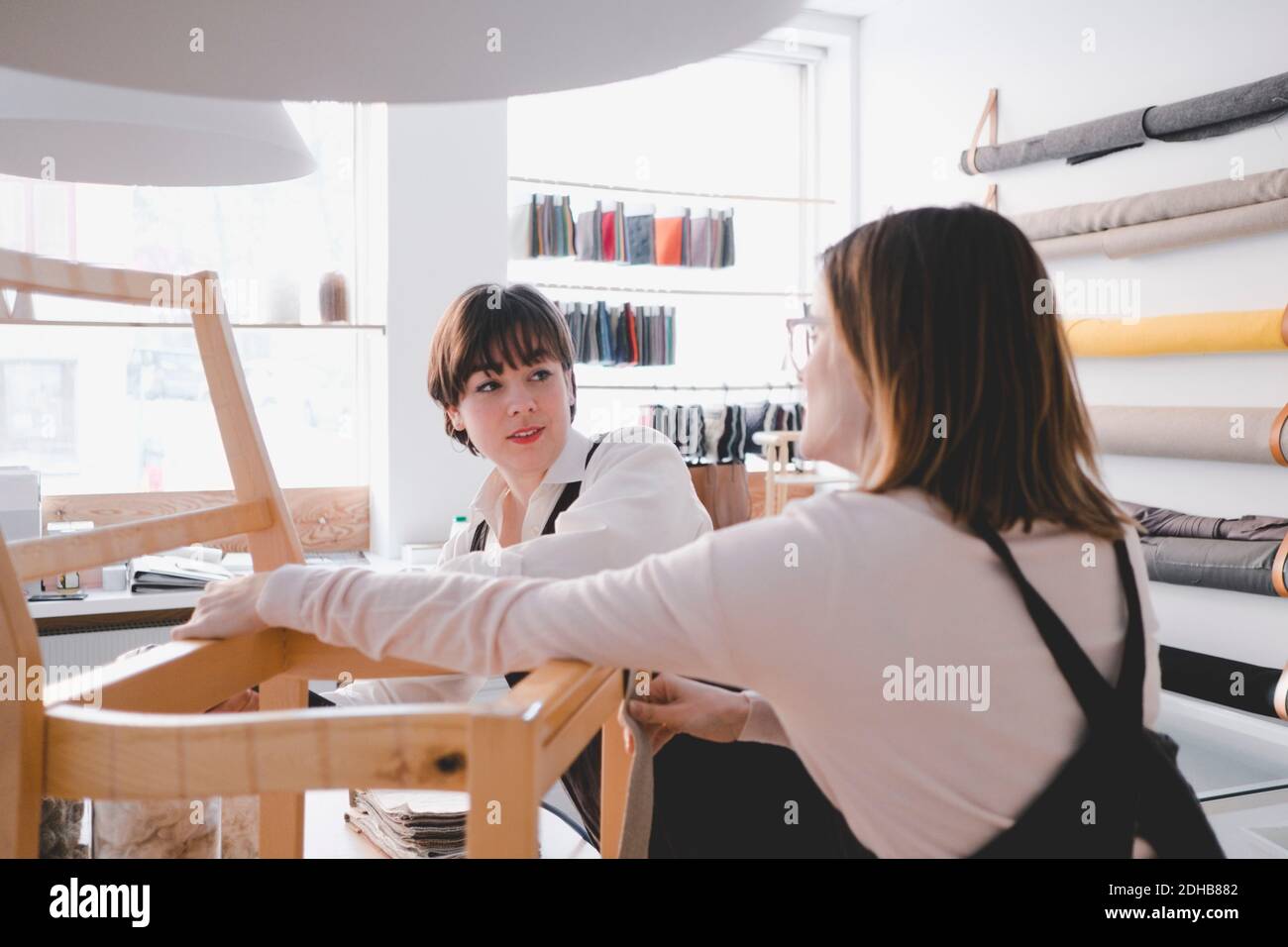Le lavoratrici per la tappezzeria lavorano sulla sedia in officina Foto Stock