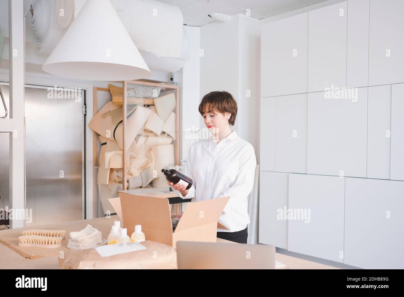 Giovane artigiano femminile che tiene una bottiglia in officina Foto Stock