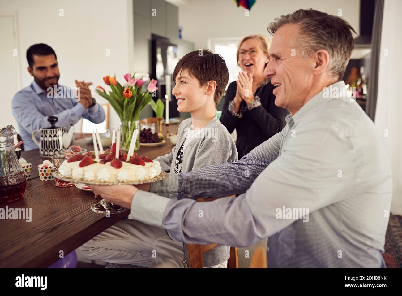 Sorridente famiglia con torta di compleanno che si gode alla festa Foto Stock