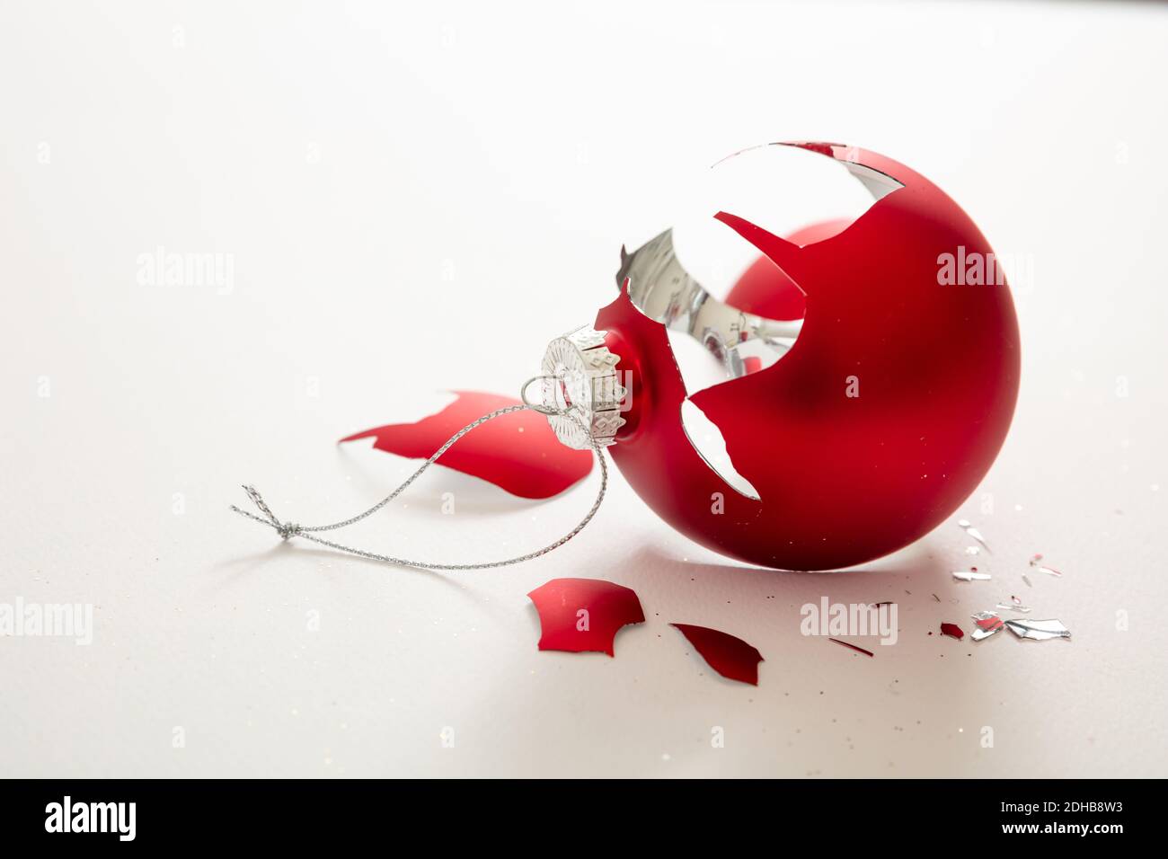 Palla di Natale rotta isolato su sfondo bianco, vista closeup. Rosso xmas bauble schiantato a pezzi. Incidente di vacanza, fragilità, rabbia concetto Foto Stock