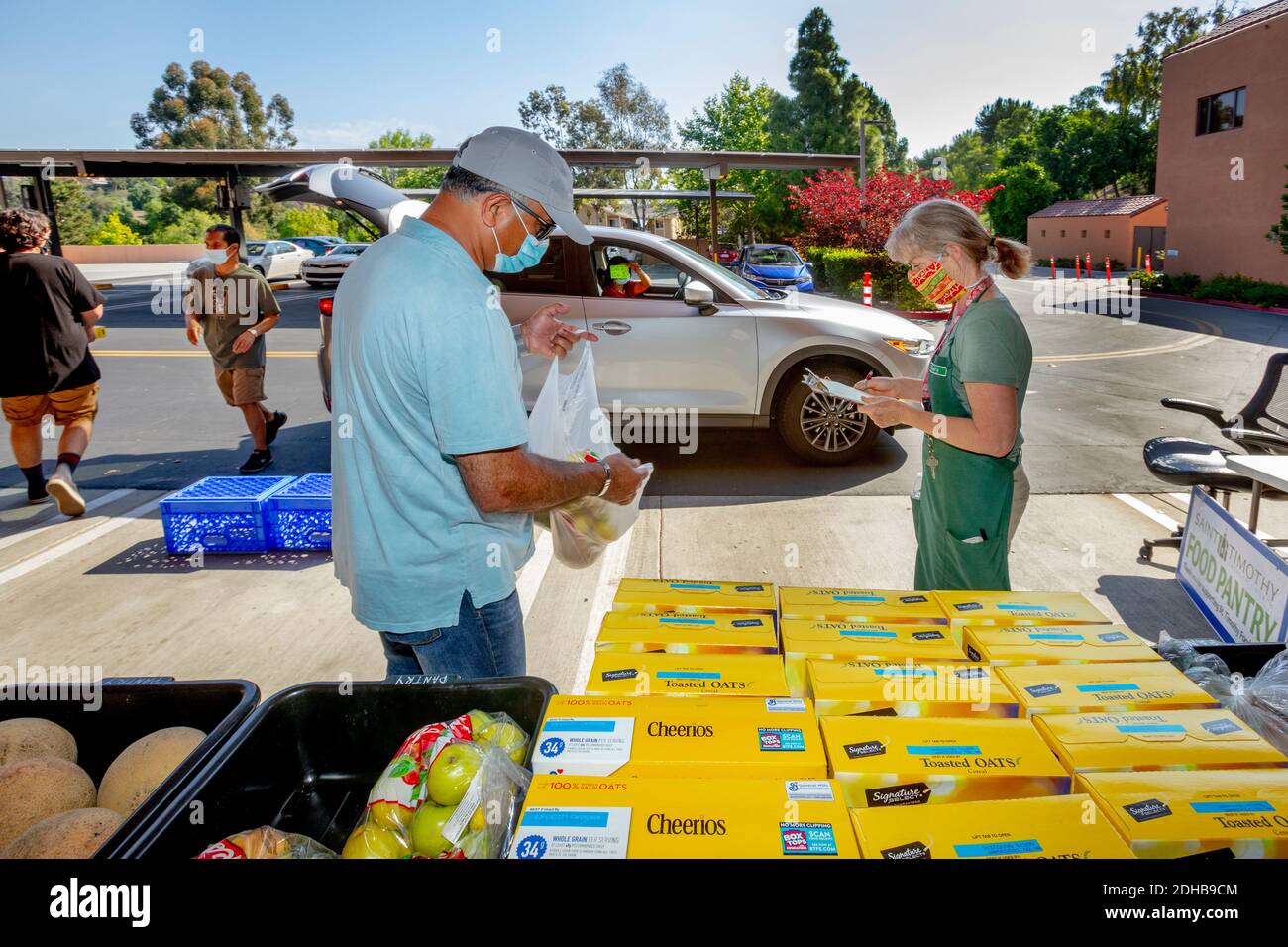 Una dispensa di cibo di beneficenza in una chiesa cattolica della California meridionale fornisce cibo alle persone bisognose utilizzando la guida attraverso la distribuzione. Si noti maschere a causa della pandemia del coronavirus. Foto Stock