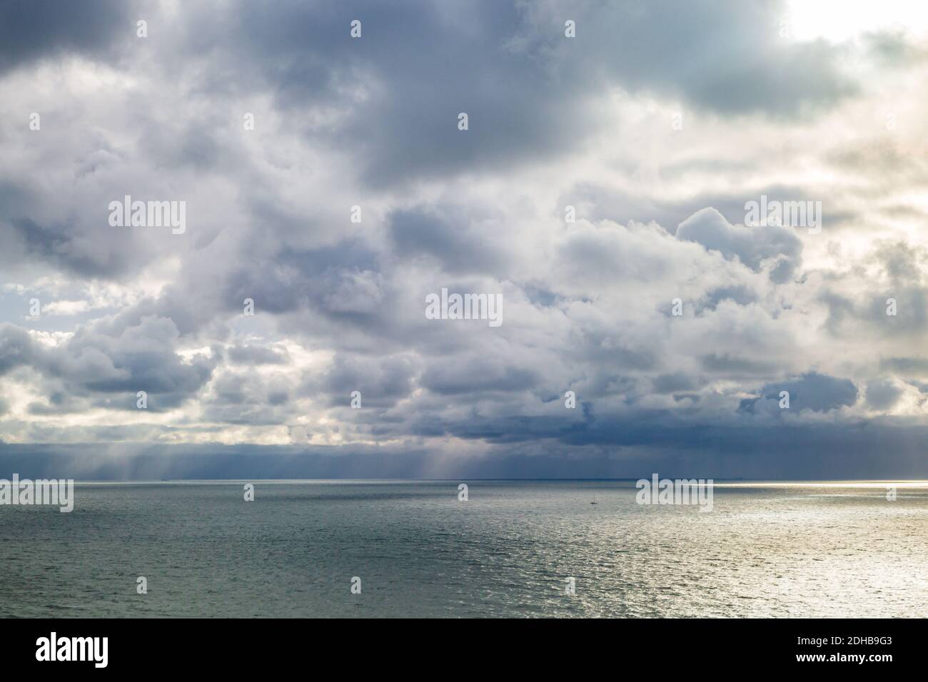 Le nubi drammatiche sull'oceano con la luce solare che splende sul acqua Foto Stock