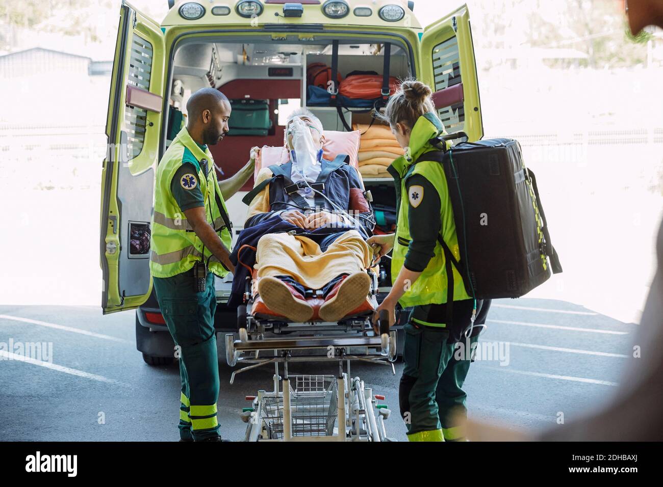 Paramedici maschili e femminili che spingono l'uomo d'affari contro i gurney dell'ospedale ambulanza Foto Stock