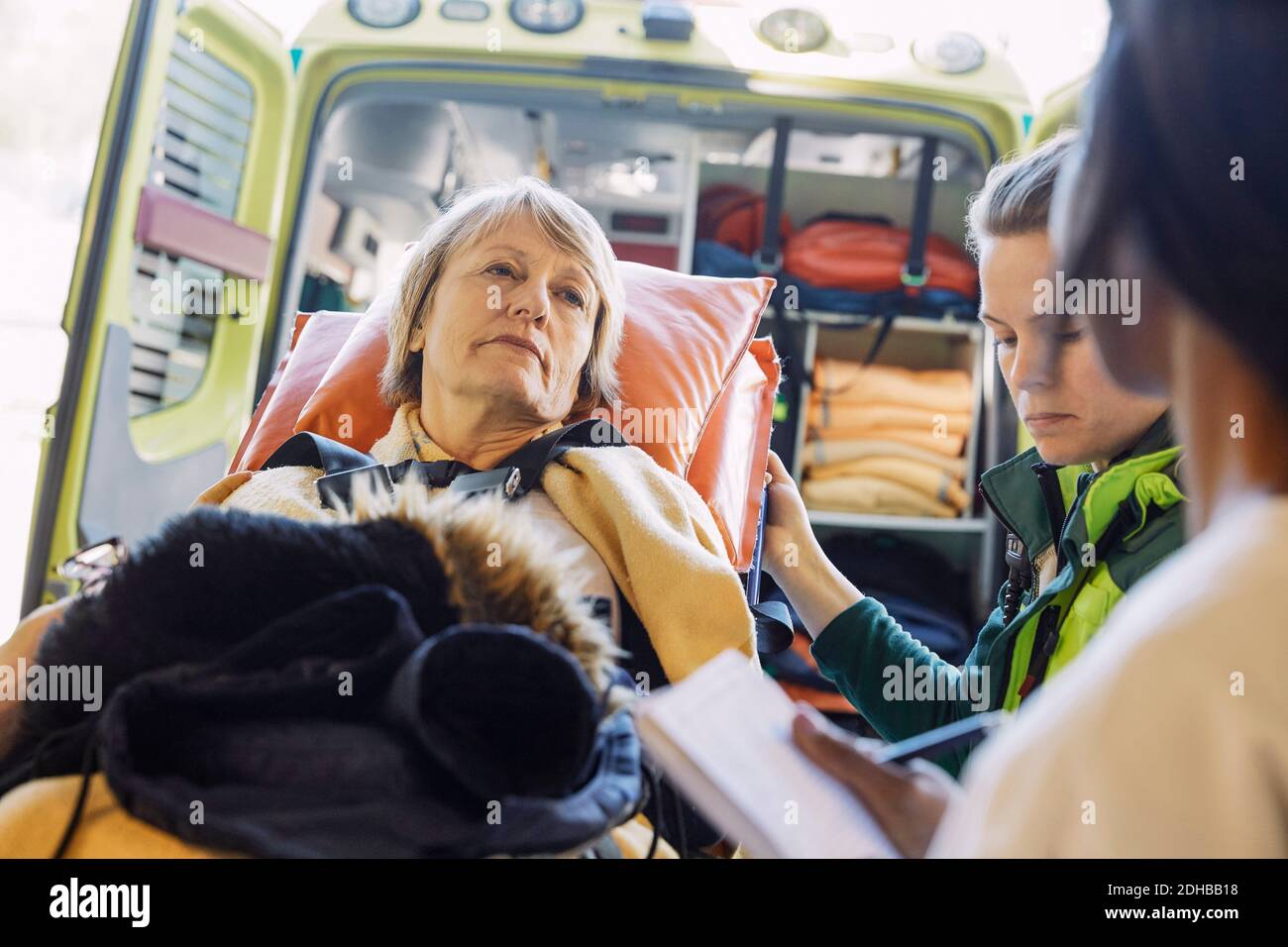 Paziente femminile maturo in ospedale gurney guardando il medico contro ambulanza Foto Stock