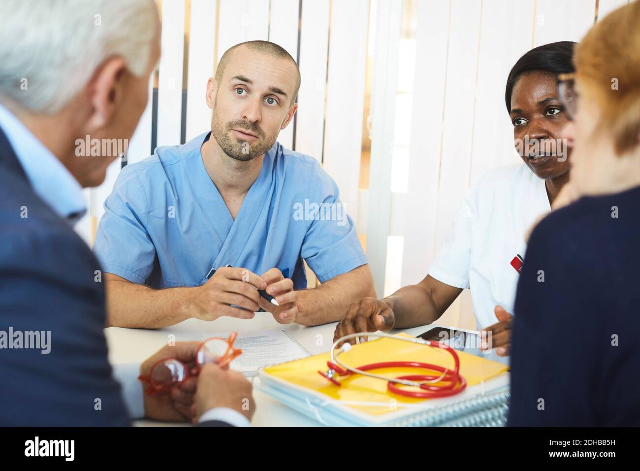 I medici ascoltano la coppia mentre siedono al tavolo durante la visita in ospedale Foto Stock