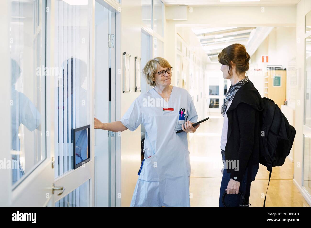 Donna medico con tablet digitale saluto donna durante la visita di routine in clinica Foto Stock