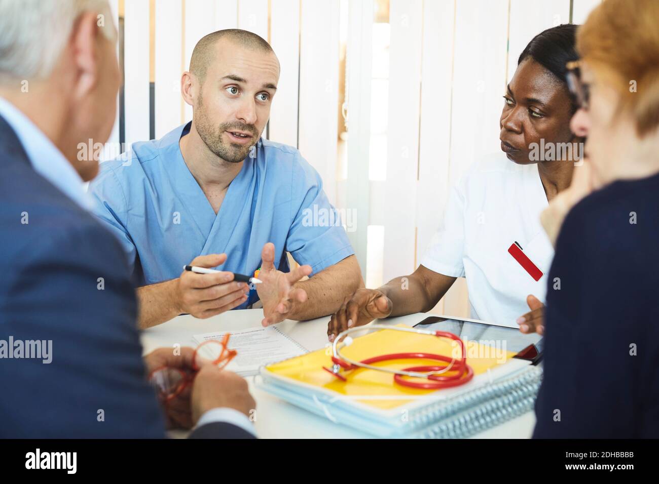 Medici di sesso maschile e femminile che discutono con l'uomo e la donna durante visita in clinica Foto Stock