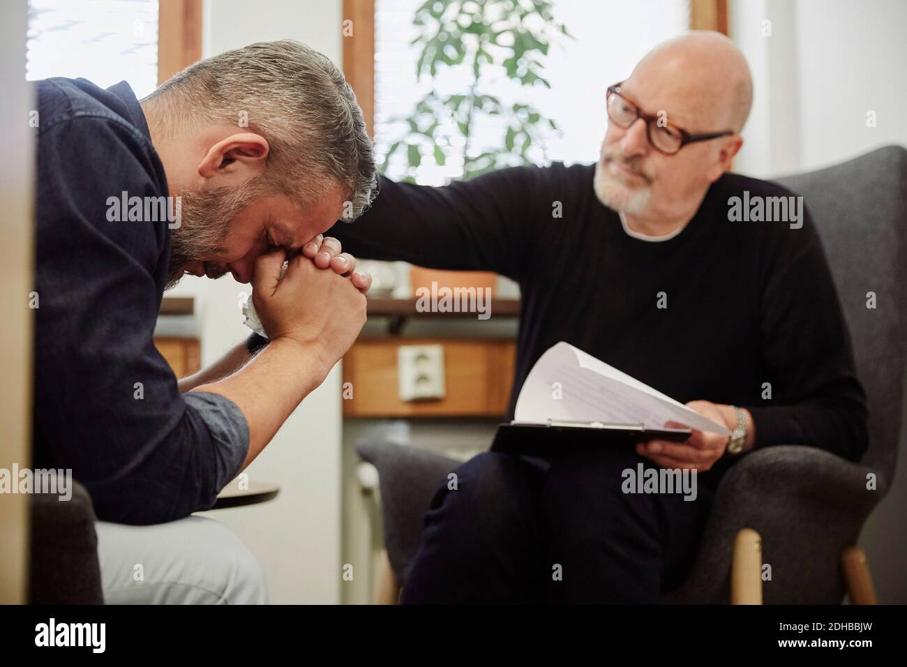 L'uomo depresso piangendo mentre il terapeuta lo consolava al centro della comunità Foto Stock