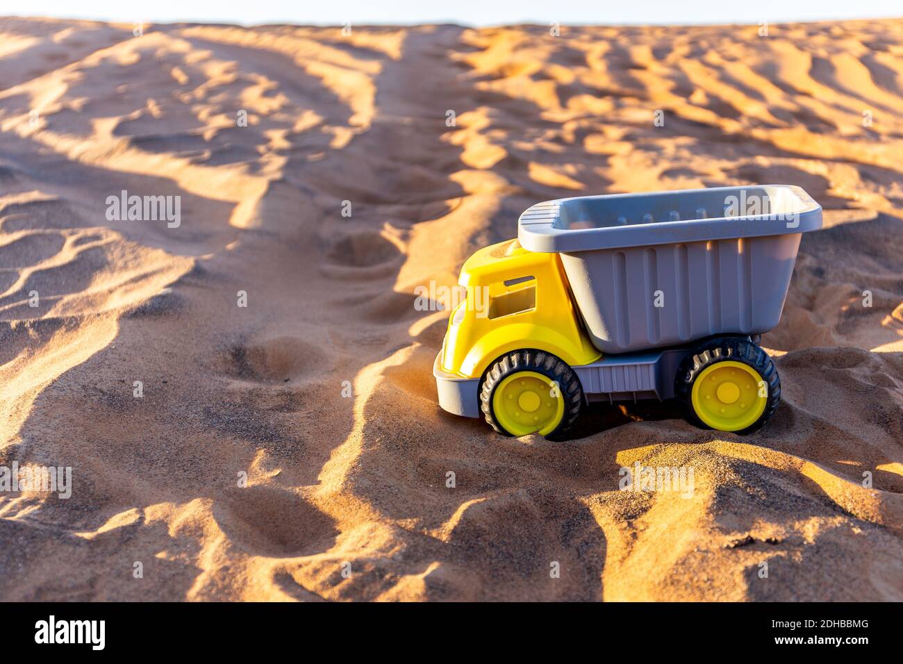 Giocattolo giallo carico e scarico camion sulla sabbia nel deserto. Foto Stock