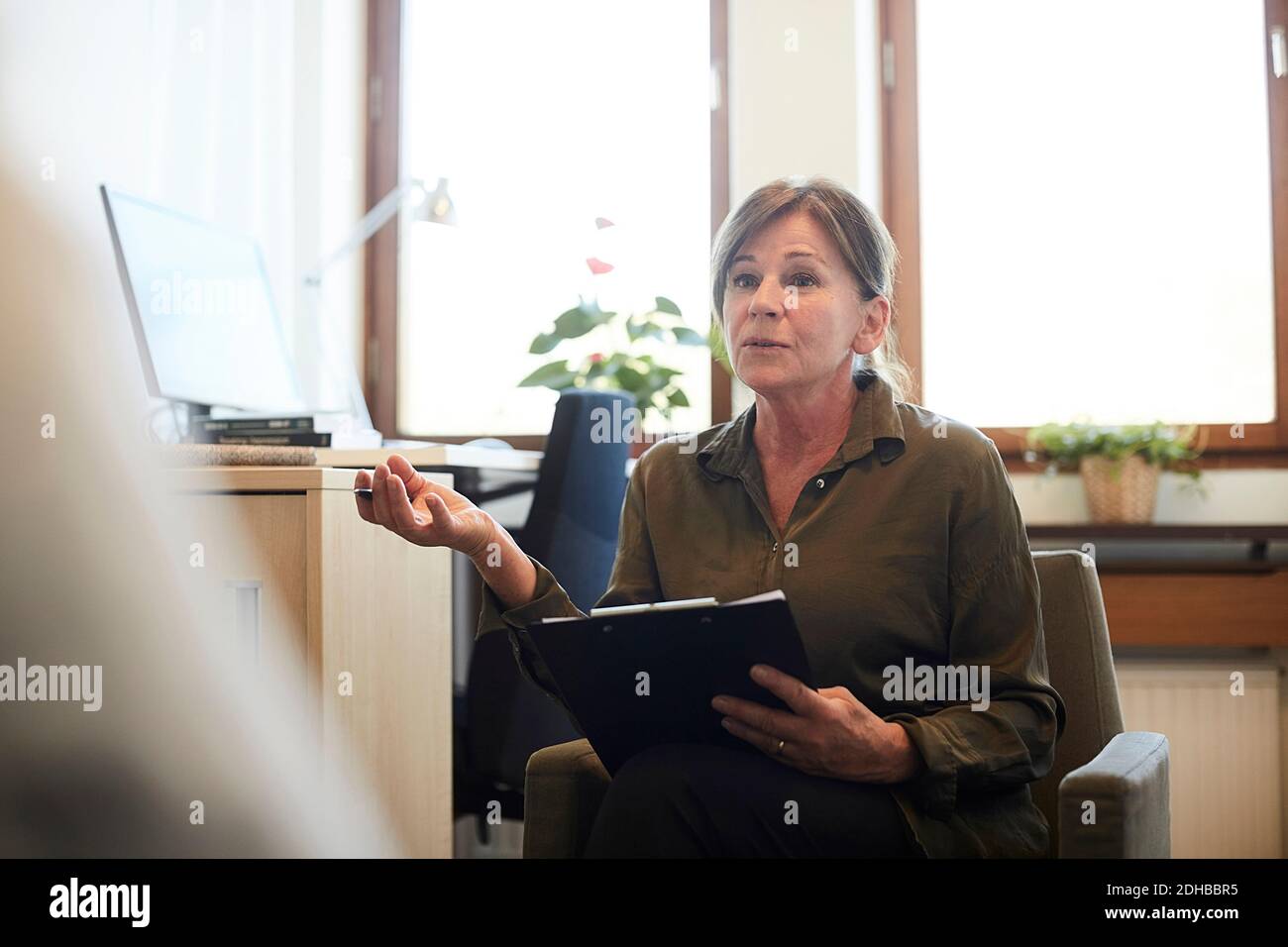 Consulente senior fiducioso che discute con il paziente in officina Foto Stock