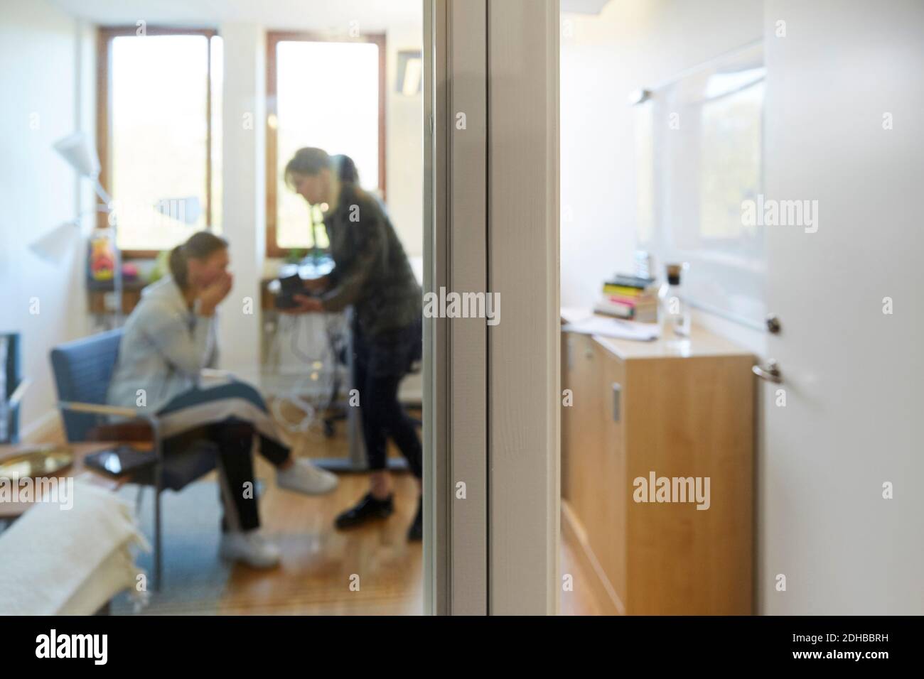 Terapista e paziente durante la sessione visto attraverso la porta di vetro Foto Stock