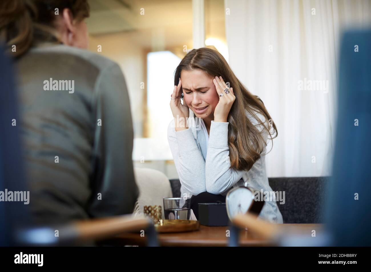Stressato piangendo adolescente con testa in mani che condividono i problemi con terapista al centro benessere Foto Stock