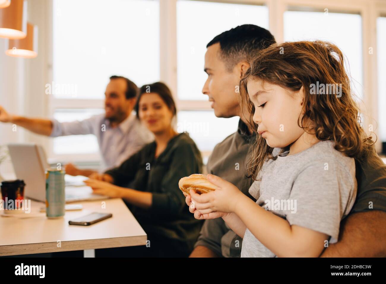 Uomo d'affari che porta il figlio che mangia la pistola in ufficio creativo Foto Stock