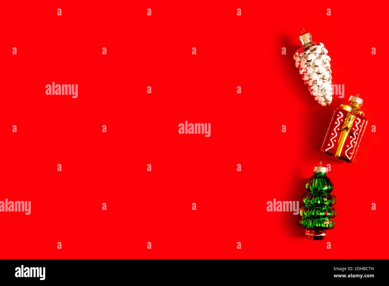 I giocattoli in vetro di Natale giacciono su sfondo rosso, vista dall'alto, spazio per il testo, spazio per la copia. Cono in abete, albero di Natale, regalo Foto Stock