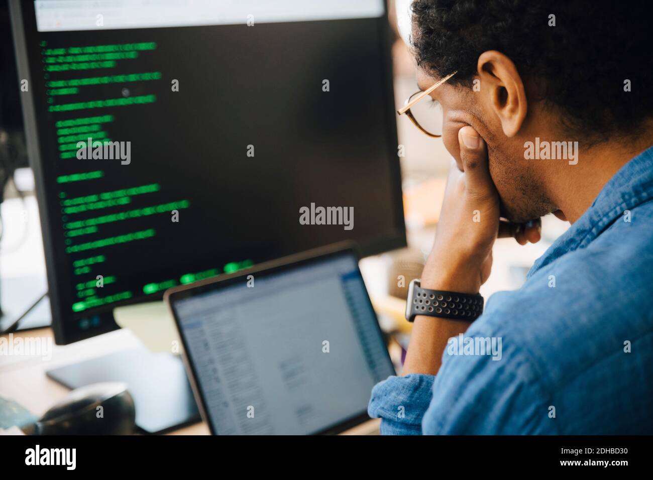 Professionista IT maschile concentrato utilizzando il computer portatile mentre si siede in creatività luogo di lavoro Foto Stock