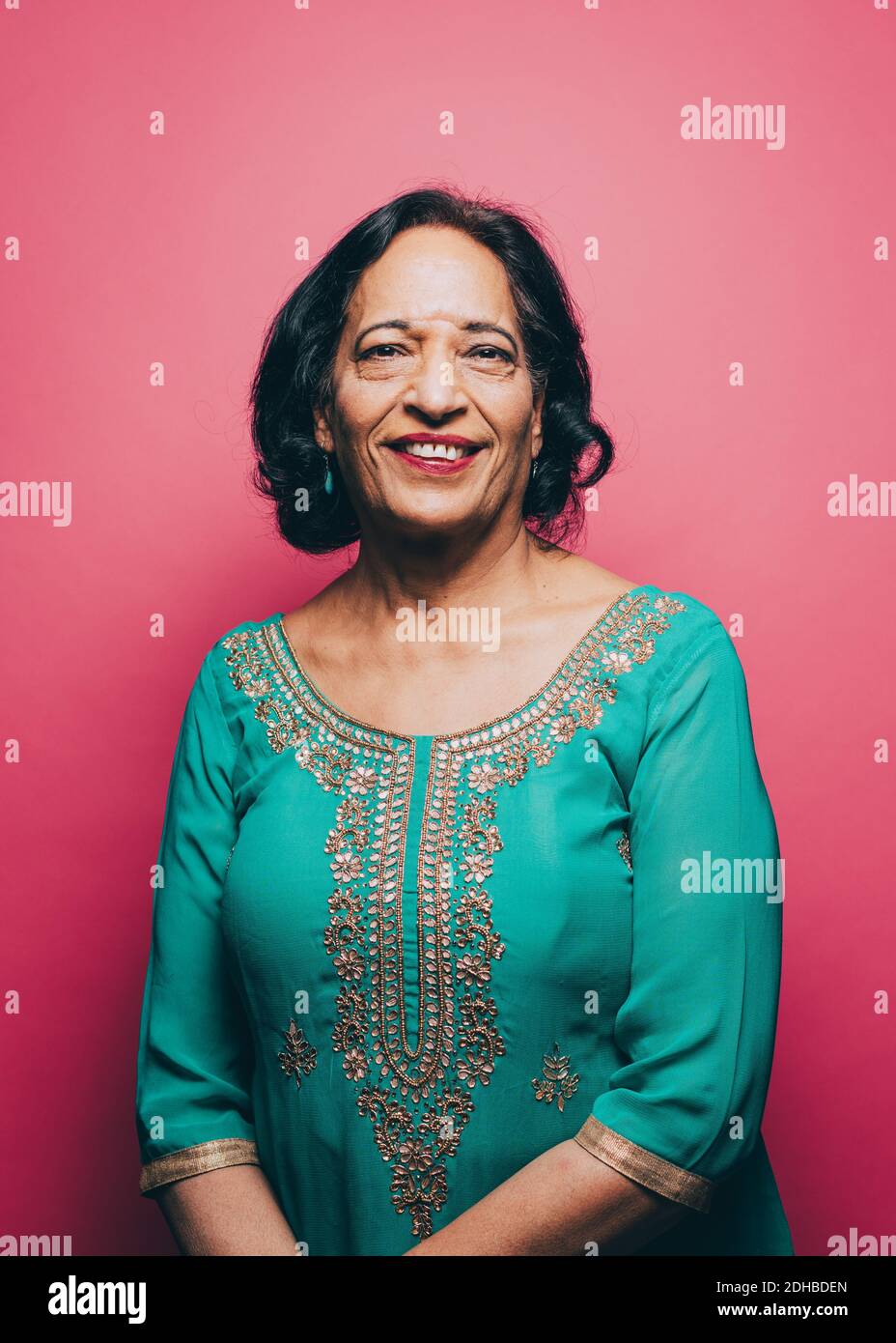 Ritratto di donna anziana sorridente che indossa salwar kameez contro il rosa sfondo Foto Stock