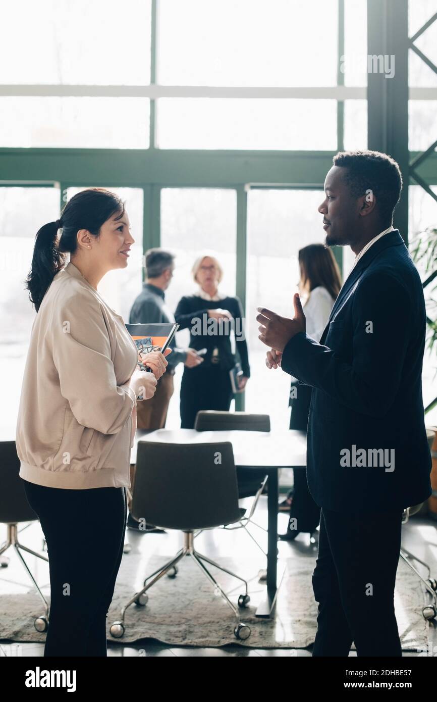 Uomo d'affari che condivide idee con una collega femminile in riunione in ufficio Foto Stock