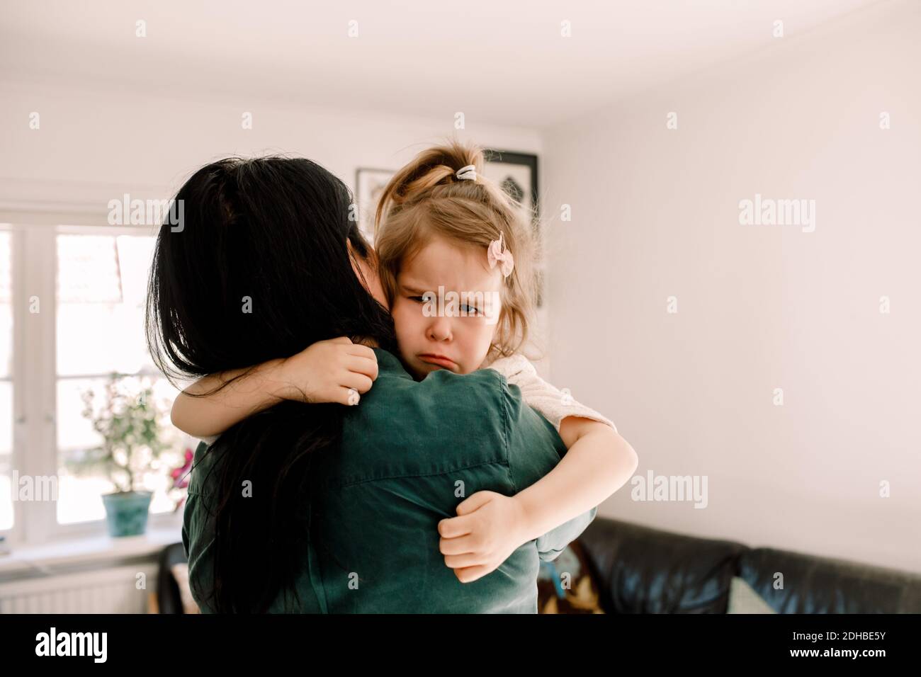 Vista posteriore di madre che porta la figlia triste mentre si sta a. casa Foto Stock