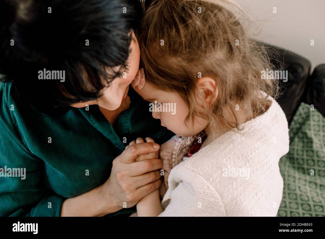 Vista ad alto angolo della madre che tiene la figlia triste mentre si siede a casa Foto Stock
