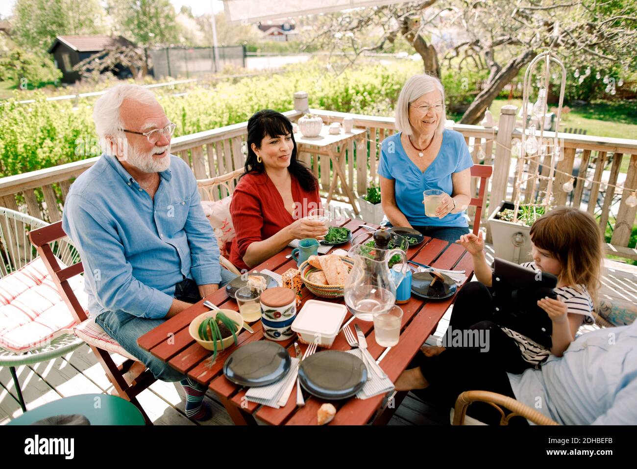 Famiglia multigenerazionale che gode di cibo al tavolo nel patio Foto Stock