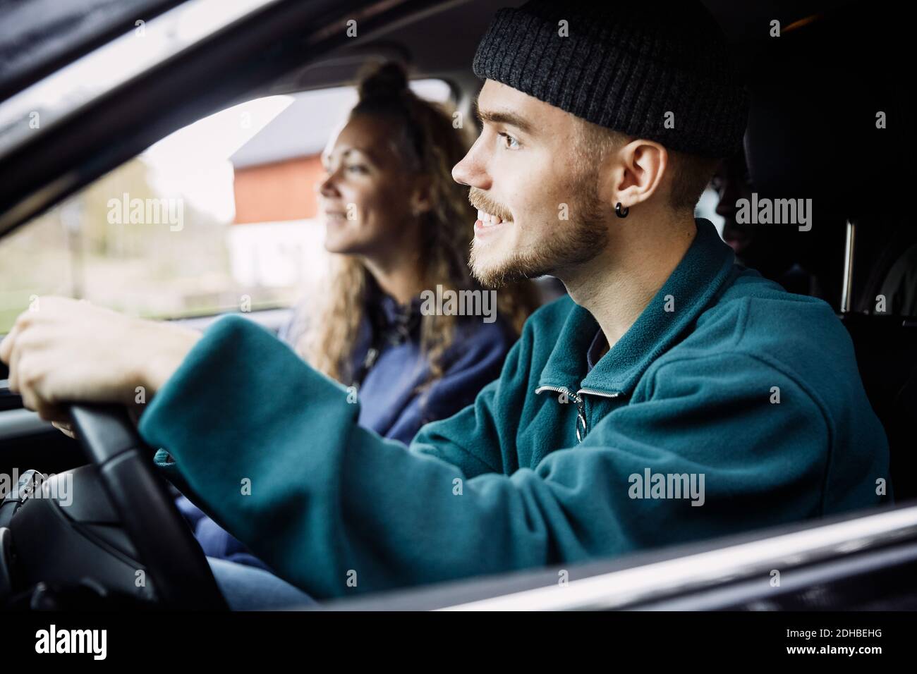 Amici felici che guardano via mentre si viaggia in auto visto attraverso finestra Foto Stock