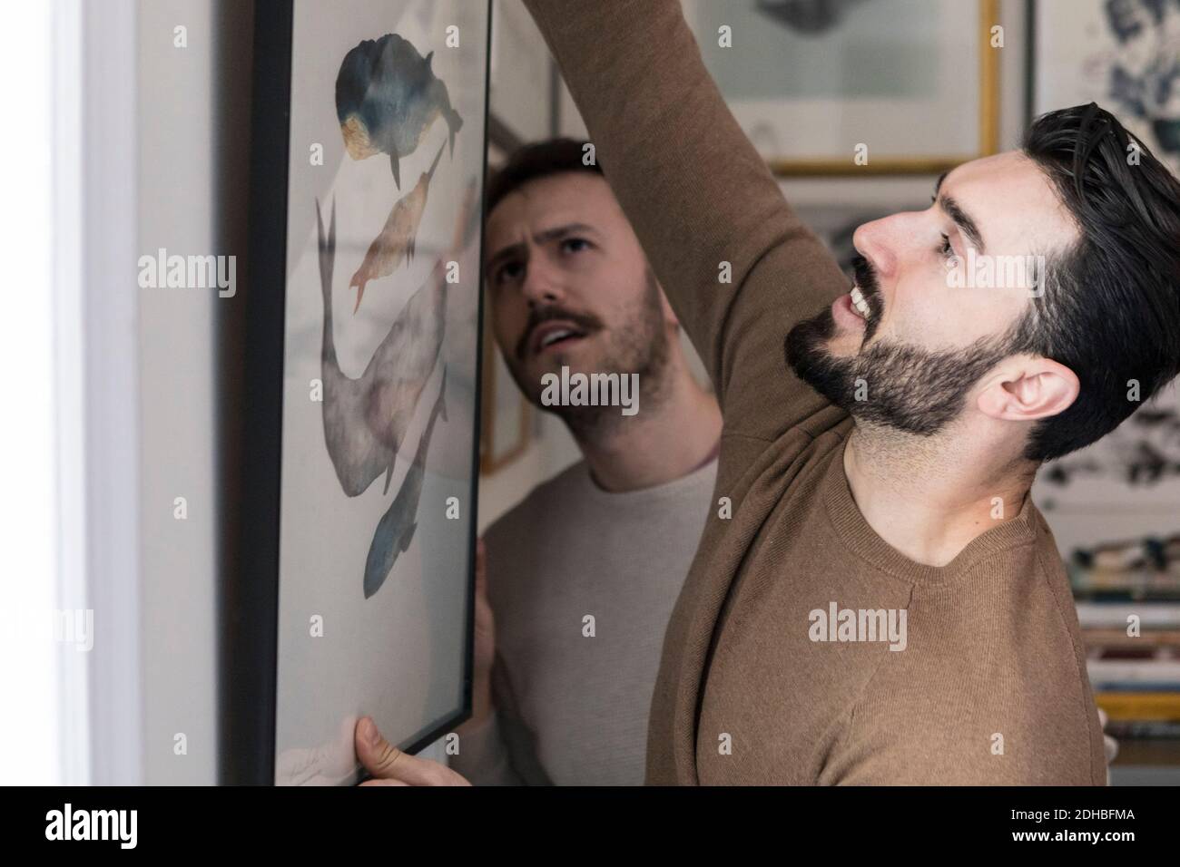 Giovane coppia gay appeso pittura a muro a casa Foto Stock
