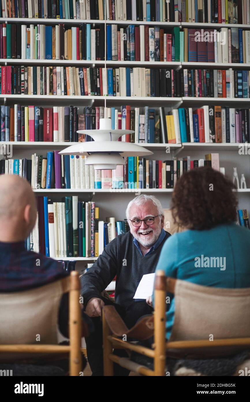 Sorridente terapeuta senior che spiega l'analisi alla coppia in ufficio a casa Foto Stock