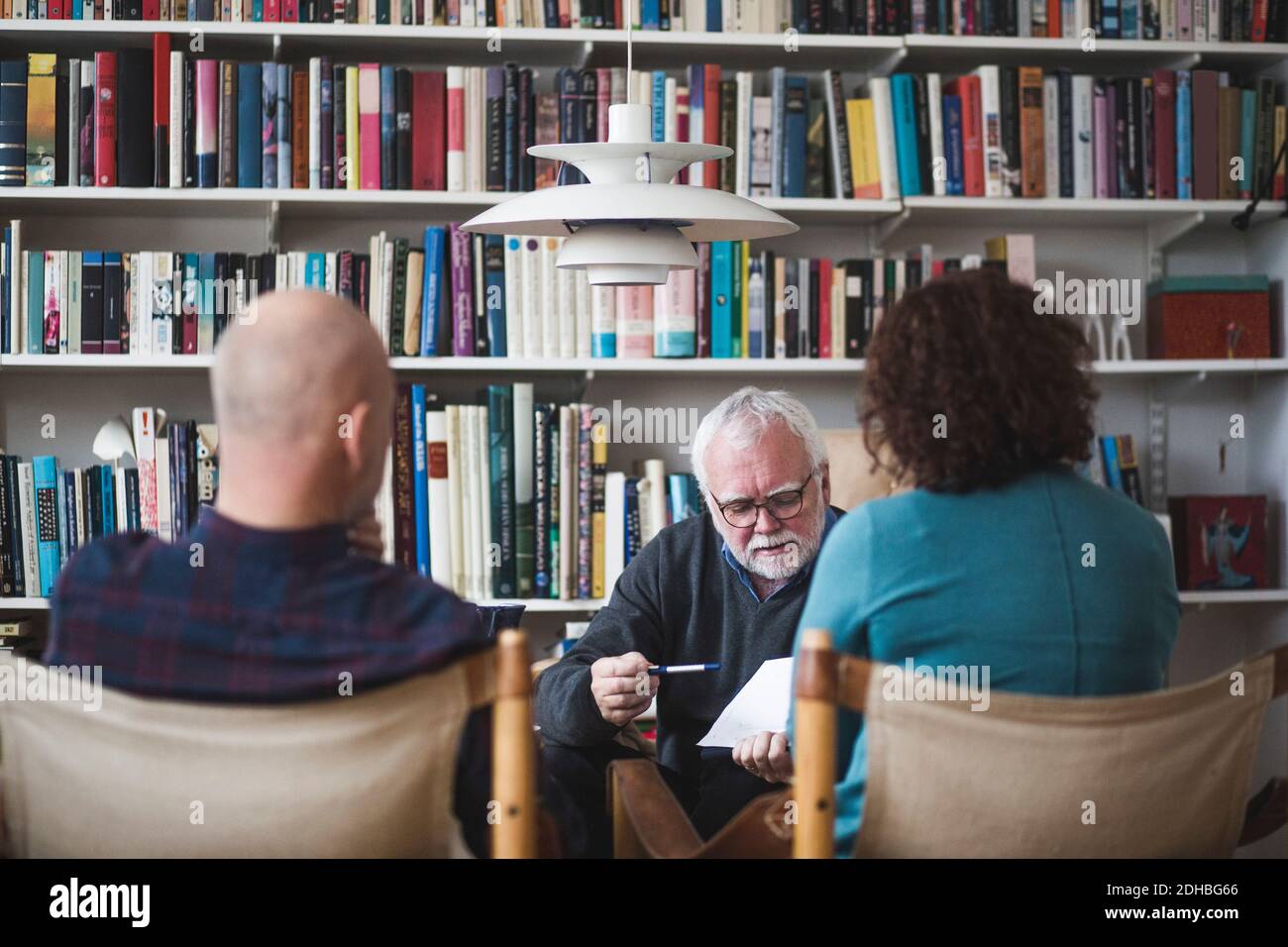 Terapista senior che spiega l'analisi per matura coppia contro libreria a. ufficio domestico Foto Stock