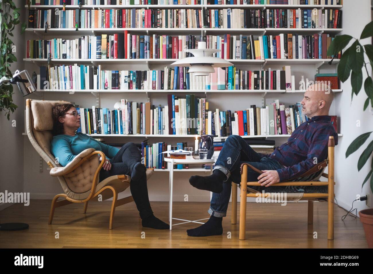 Lunghezza completa del terapeuta e paziente che discute da libreria a. ufficio domestico Foto Stock