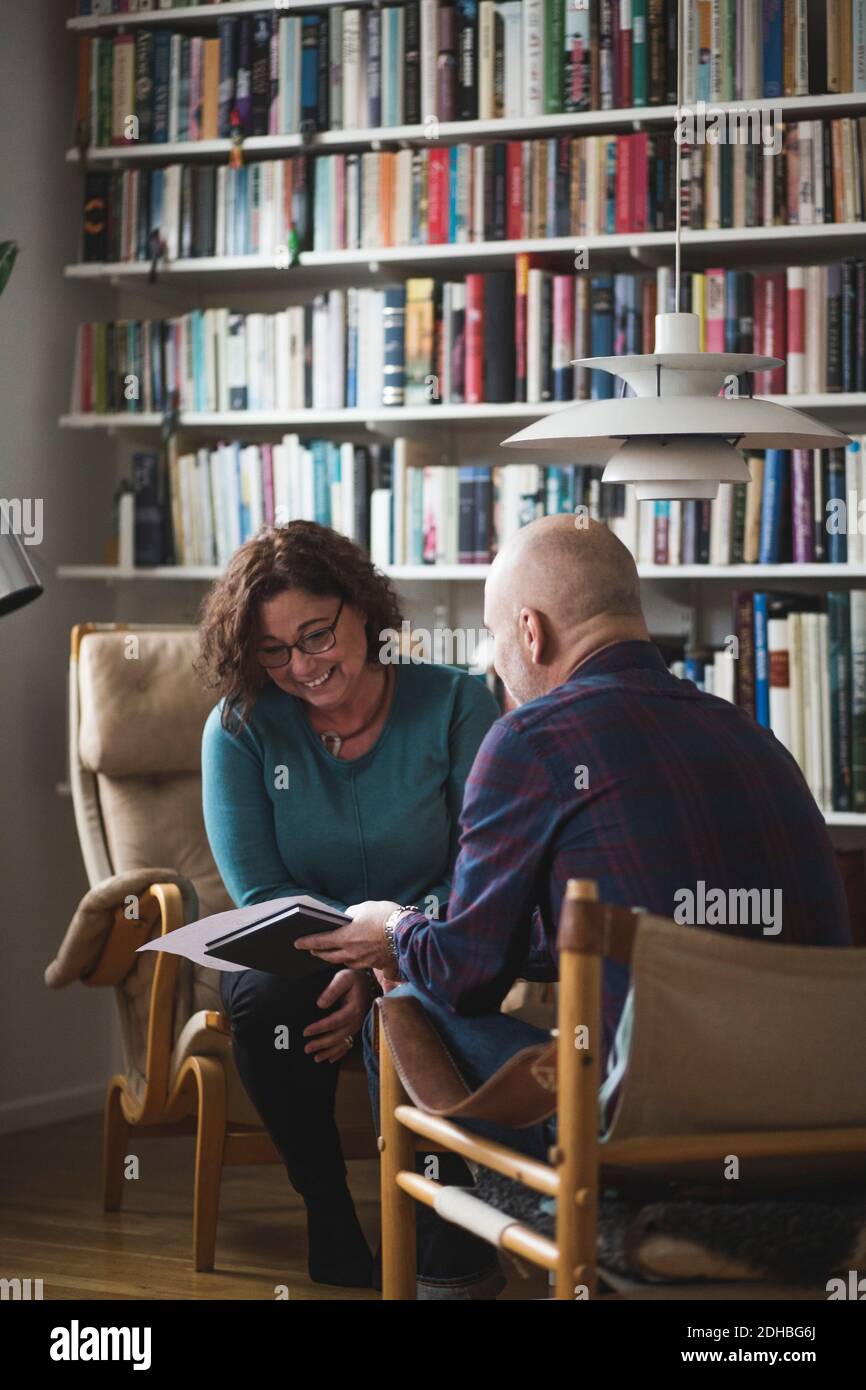 Terapeuta maschile che mostra il documento al paziente sorridente in ufficio a casa Foto Stock