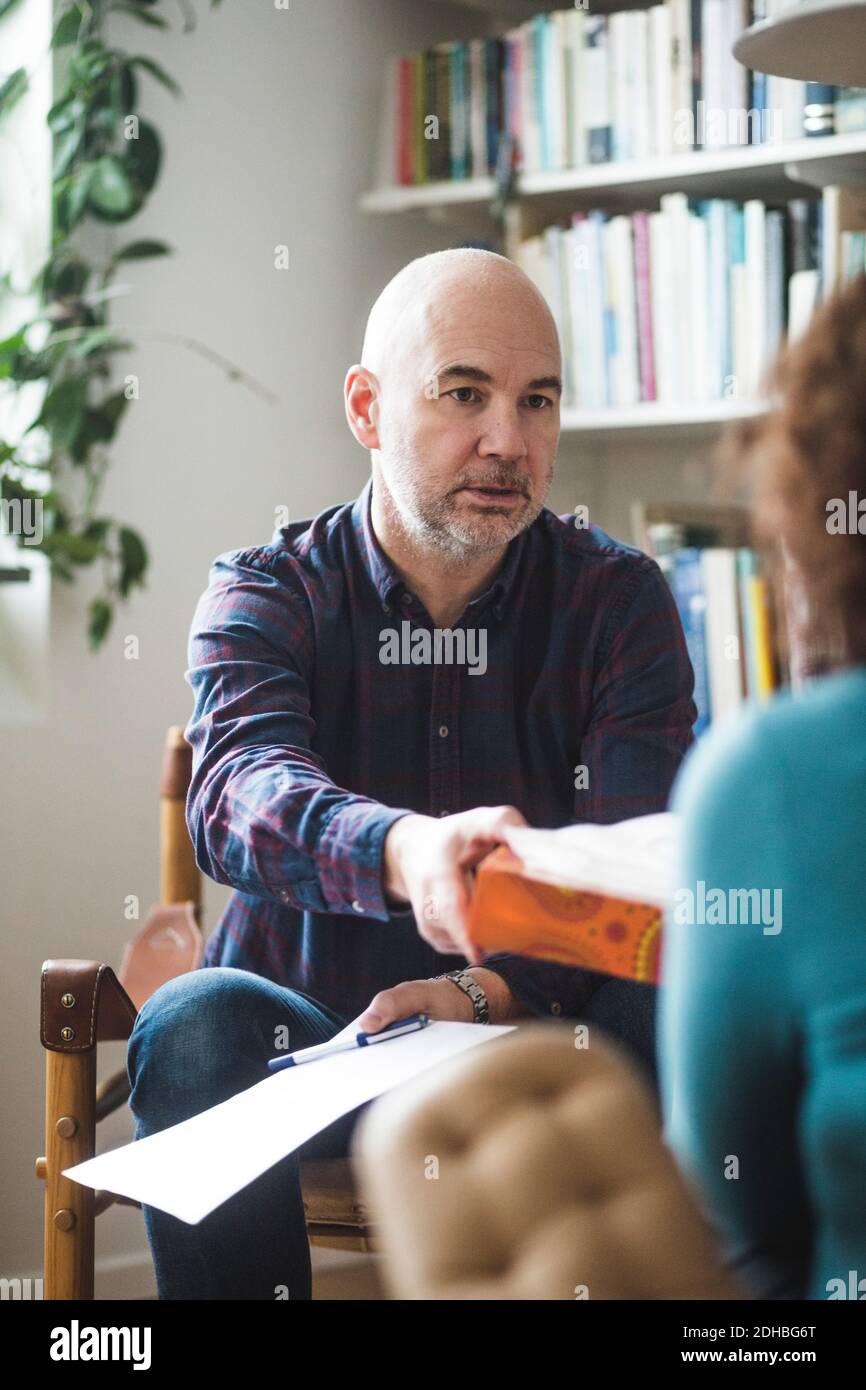 Terapeuta maschile che dà tessuto alla paziente femminile durante la sessione di terapia Foto Stock