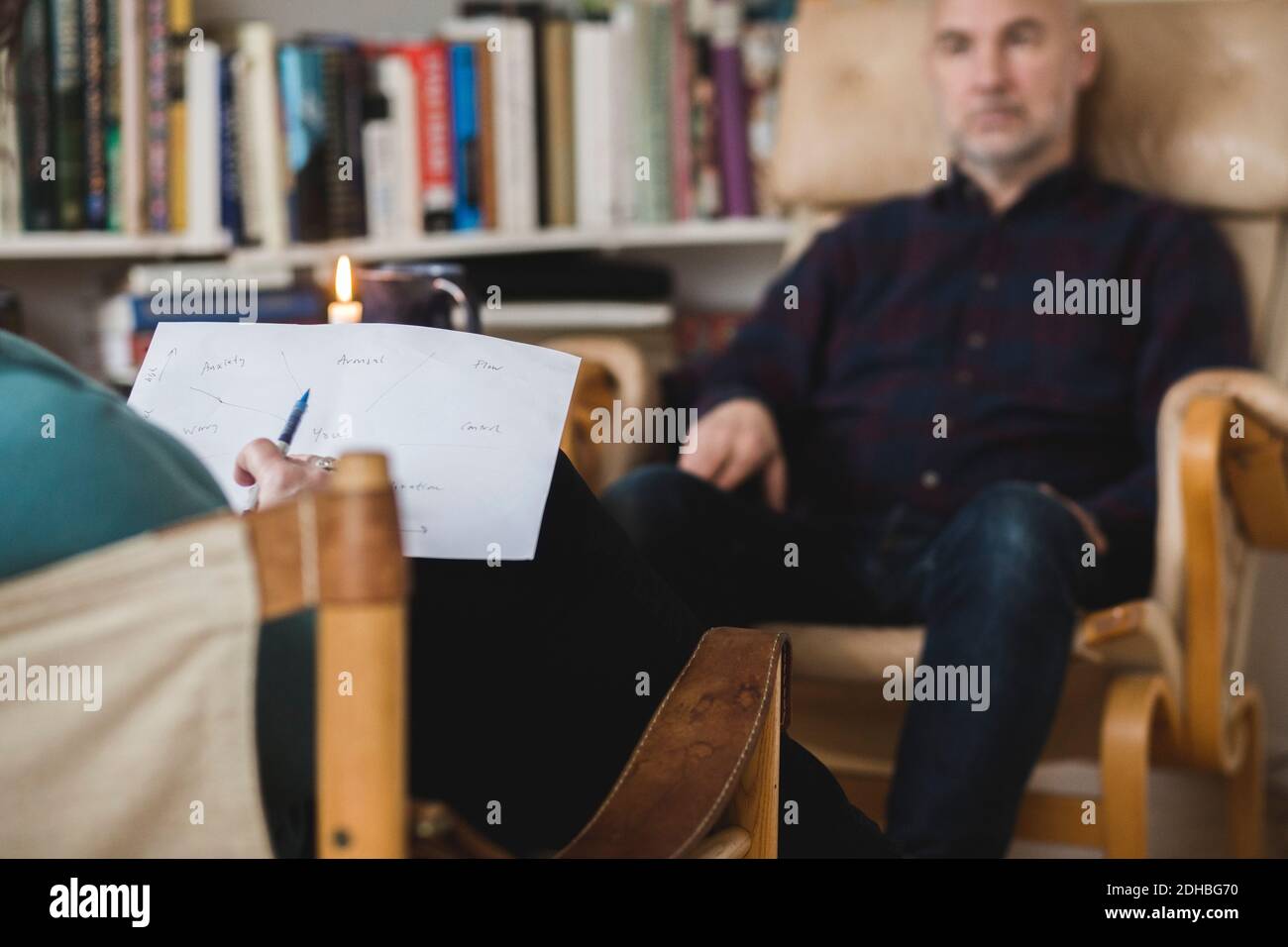 Il terapeuta legge la carta e discute con il paziente di sesso maschile durante la sessione Foto Stock