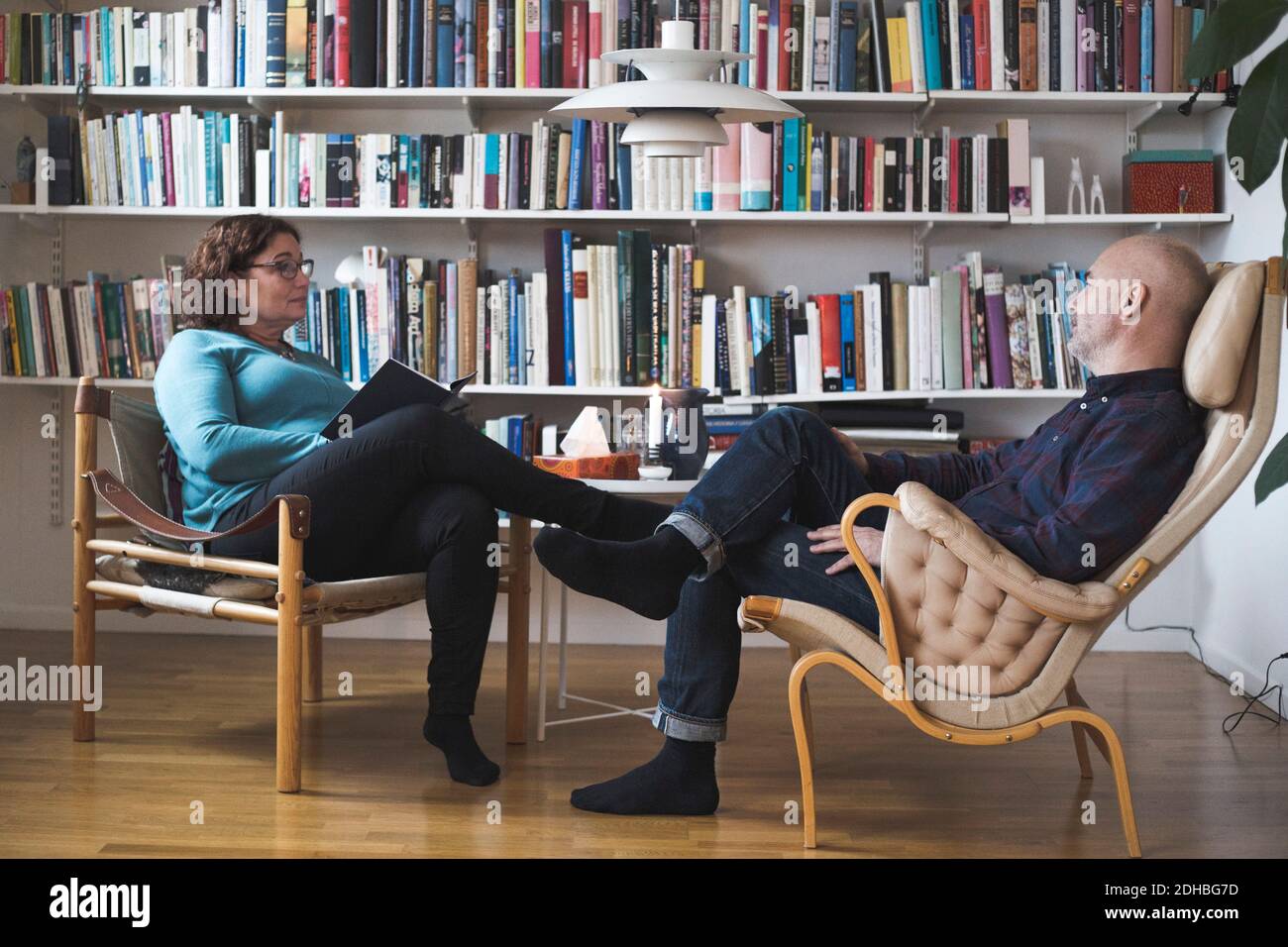 Terapeuta donna matura che parla con il paziente da libreria a casa ufficio Foto Stock