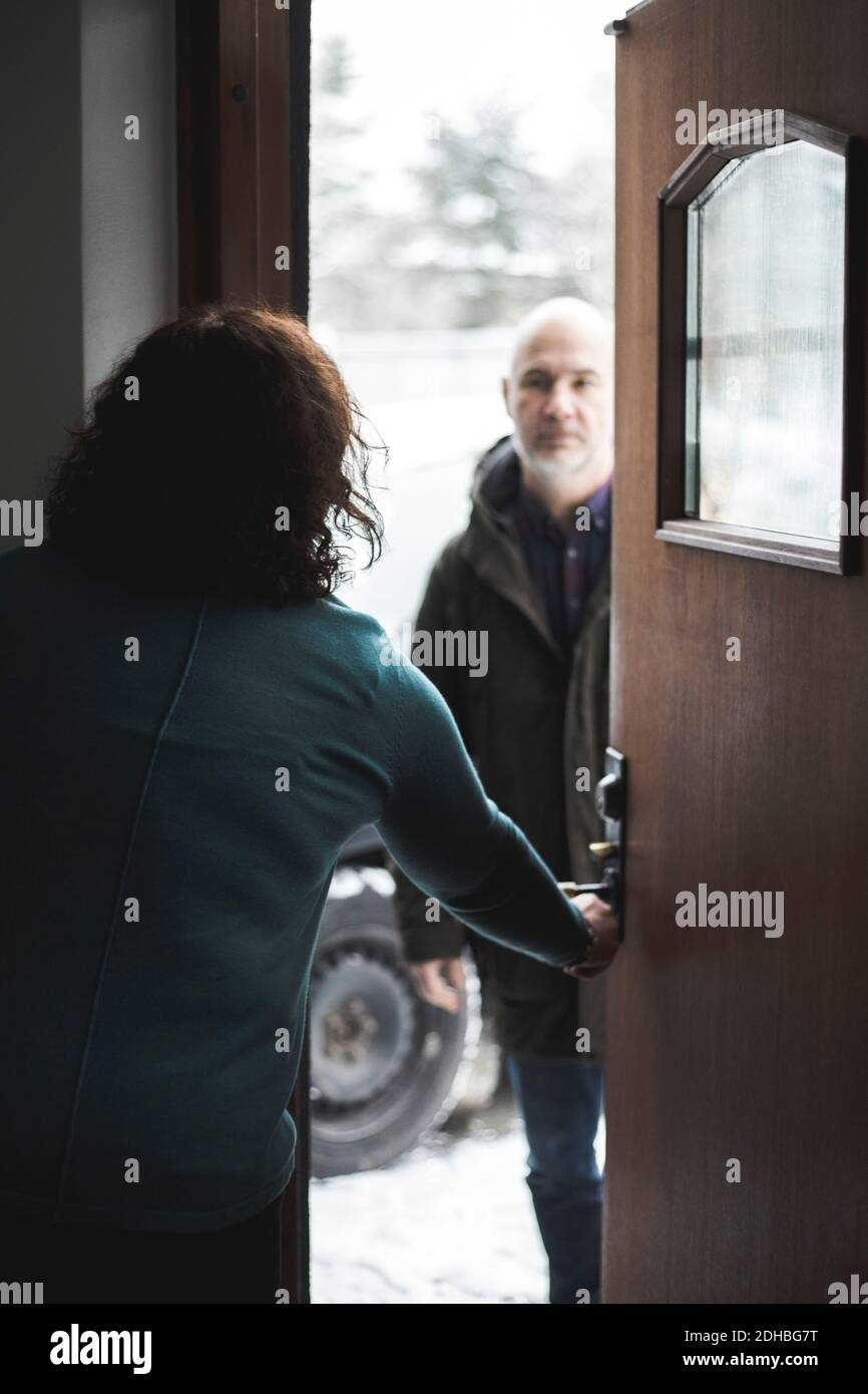 Femmina medico apertura porta per paziente maturo in ufficio domestico Foto Stock