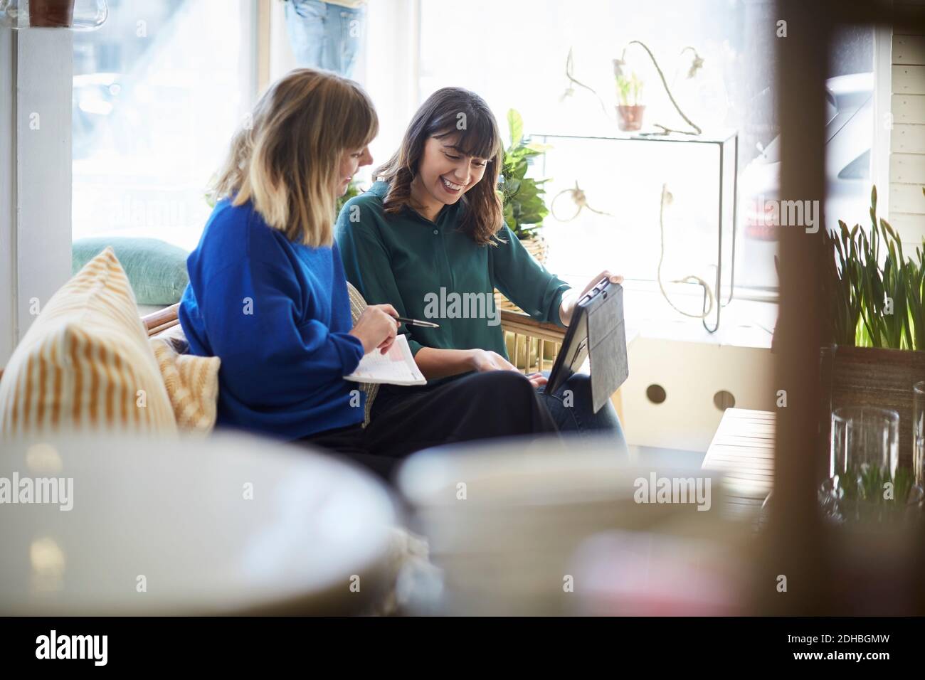 Sorridenti partner di sesso femminile che parlano di tablet digitale in boutique Foto Stock