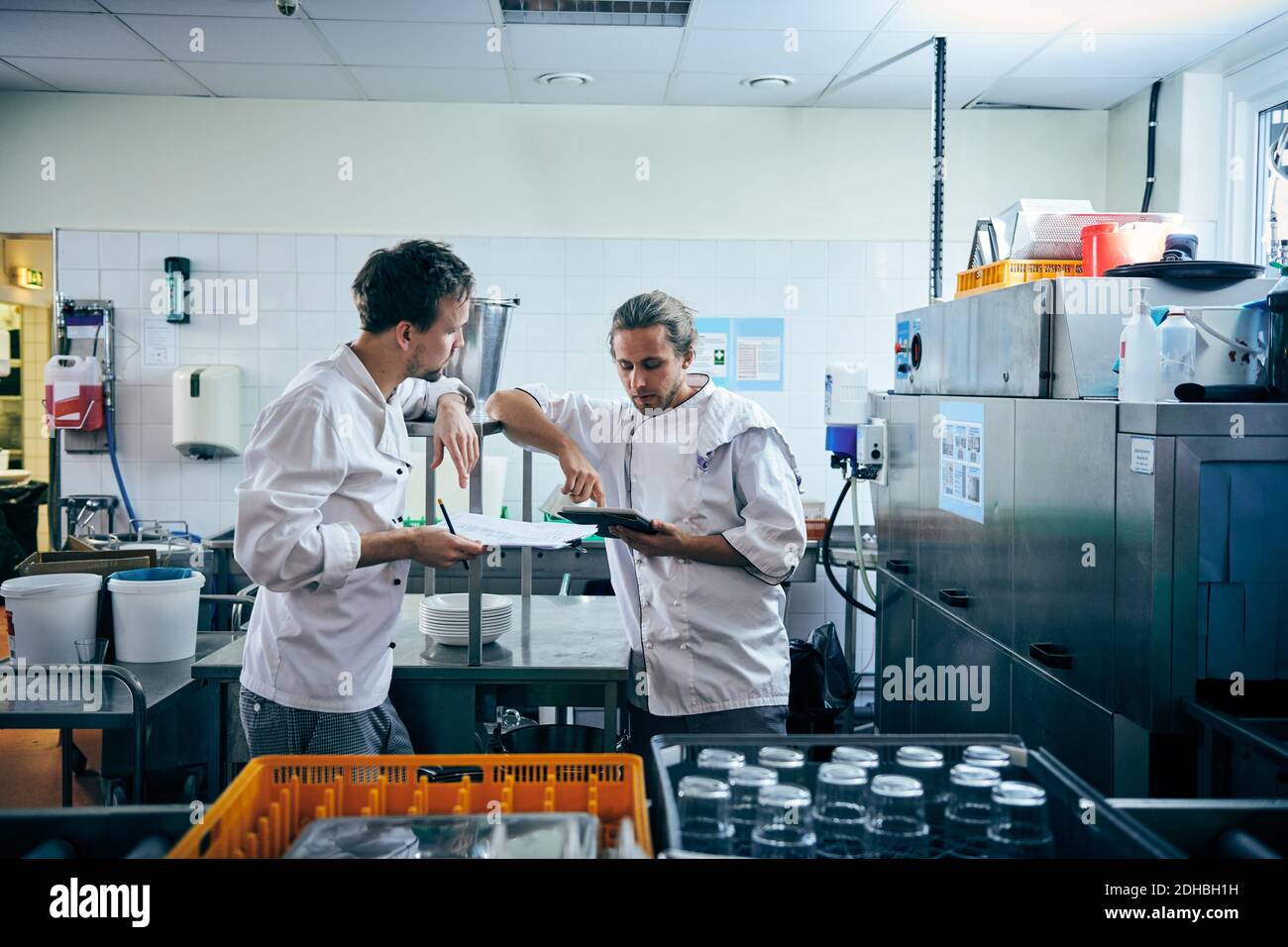 Chef maschi con tablet digitale e documenti in cucina Foto Stock