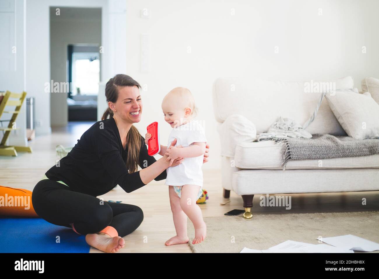 Allegra madre lavoratrice che tiene figlia mentre si esercita in soggiorno in ufficio a casa Foto Stock
