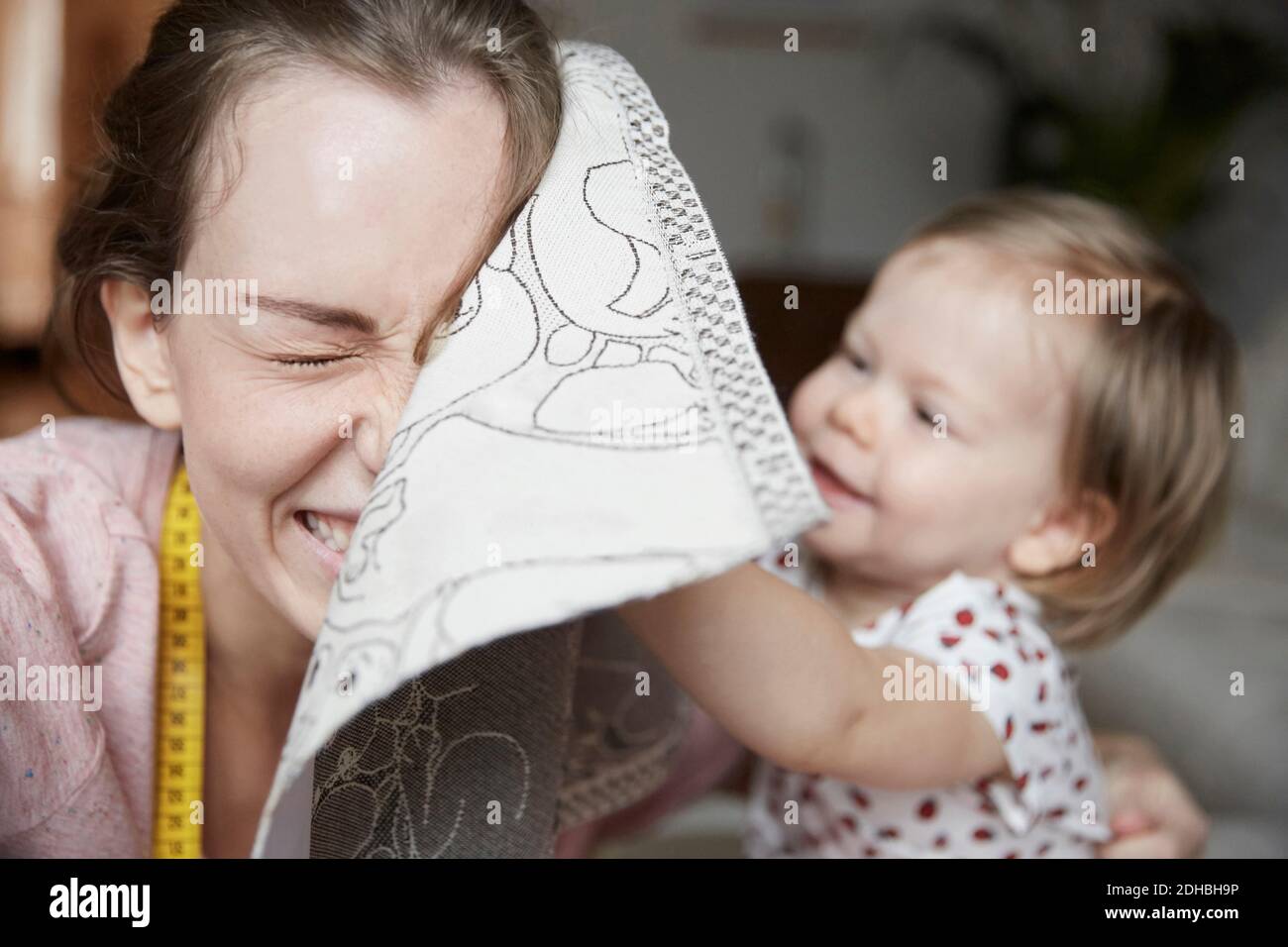 Allegro stilista di moda e figlia che gioca con stoffa a casa Foto Stock