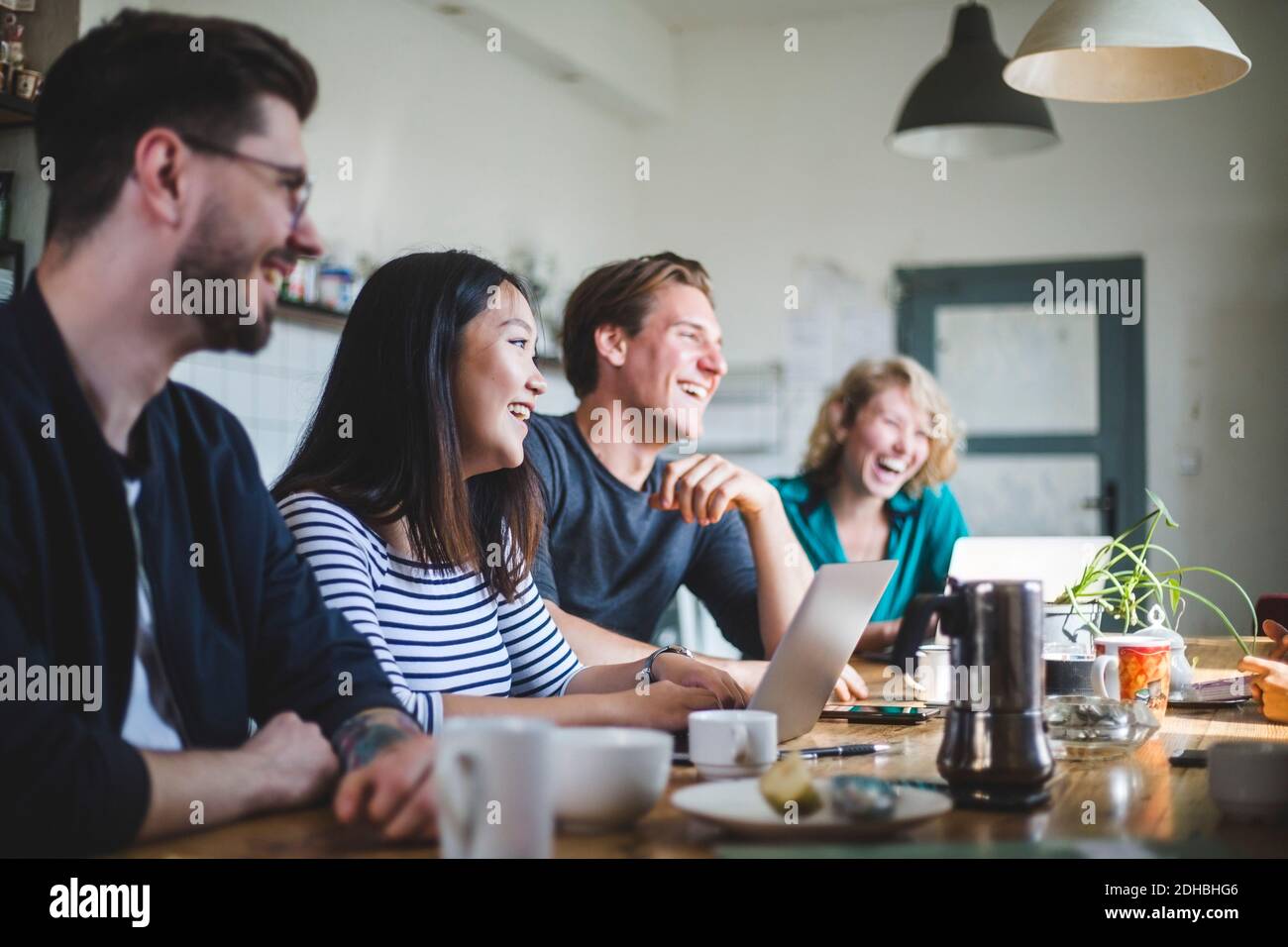 Un team di hacker professionisti che ridono mentre si siede alla scrivania in ufficio Foto Stock