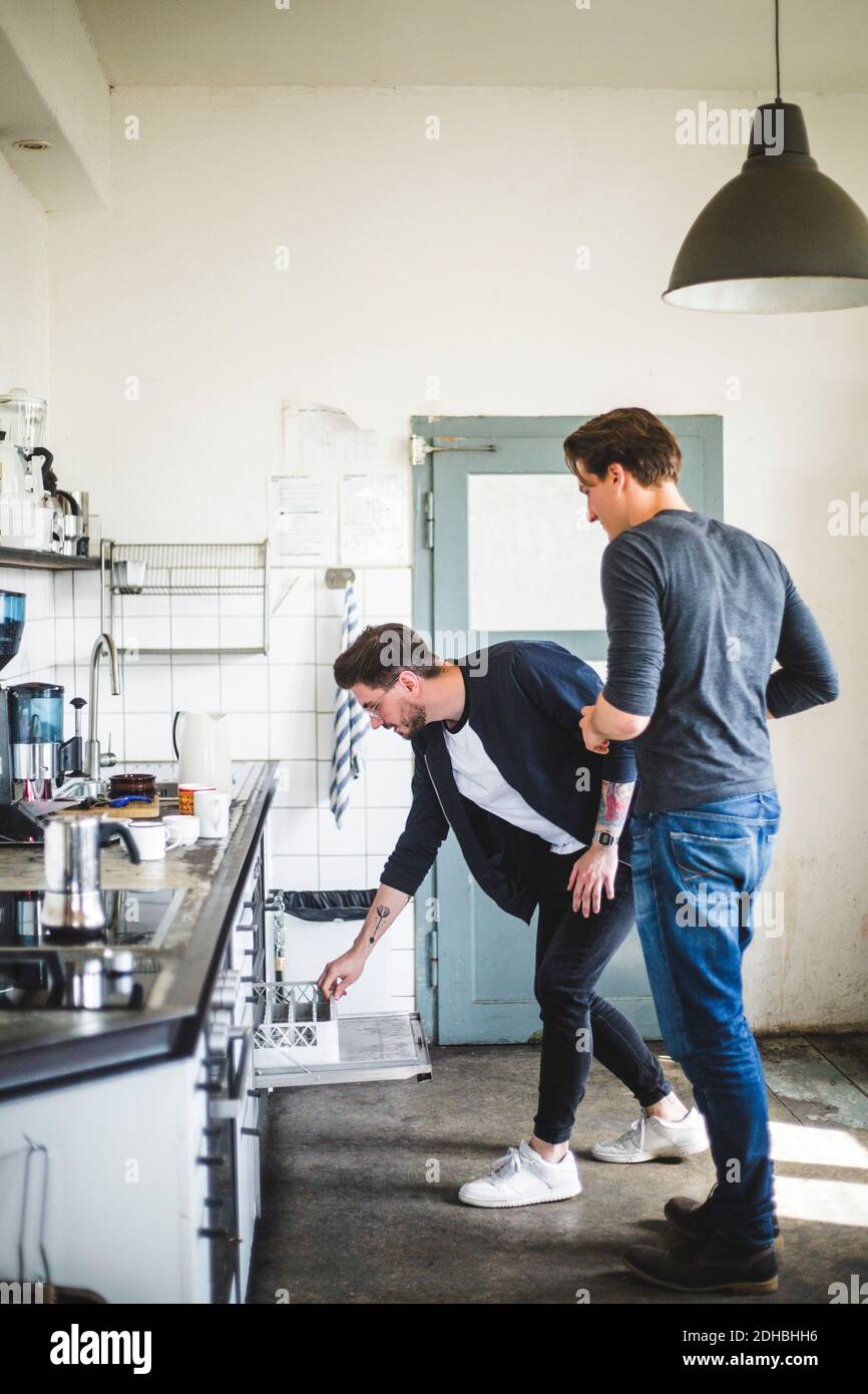 Tutta la lunghezza dei programmatori maschi che si levano in piedi in cucina al creativo ufficio Foto Stock