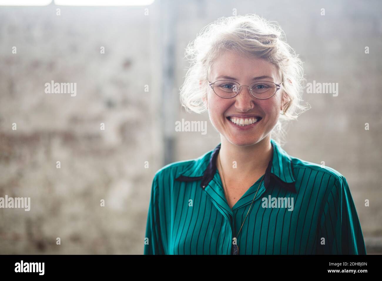 Ritratto di una donna blonde sorridente in piedi in ufficio creativo Foto Stock