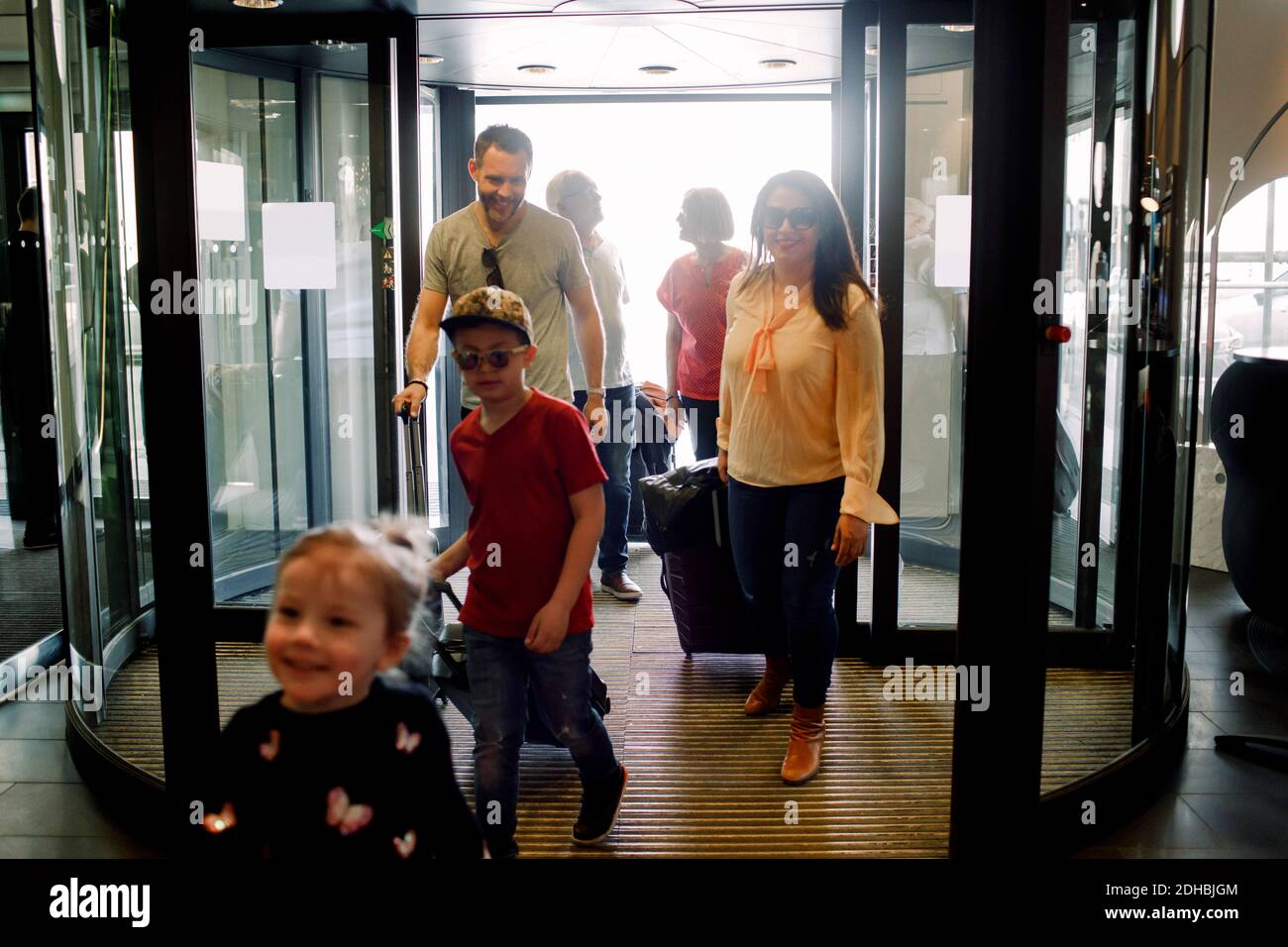 Una famiglia sorridente che entra in hotel durante le vacanze Foto Stock
