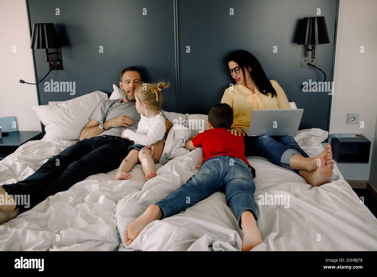 Famiglia felice a letto in camera d'albergo durante le vacanze Foto Stock